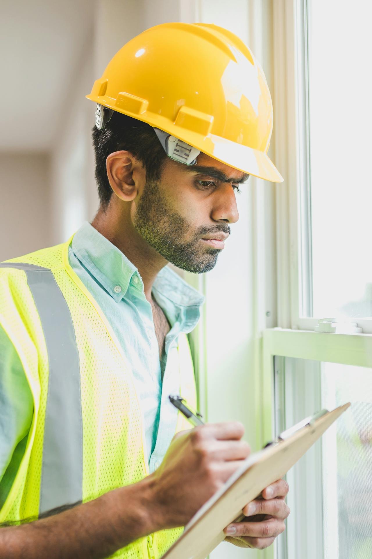 Construction project manager in hard hat reviewing clipboard at a residential build site